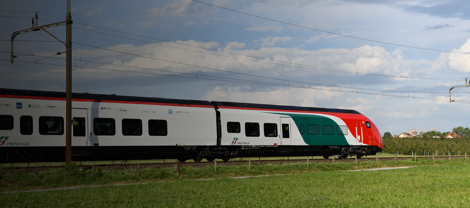 Eine Regionalbahn fährt an einer Wiese vorbei.